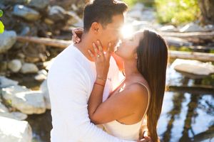 A romantic moment captured between two people during sunset near a rocky water feature.