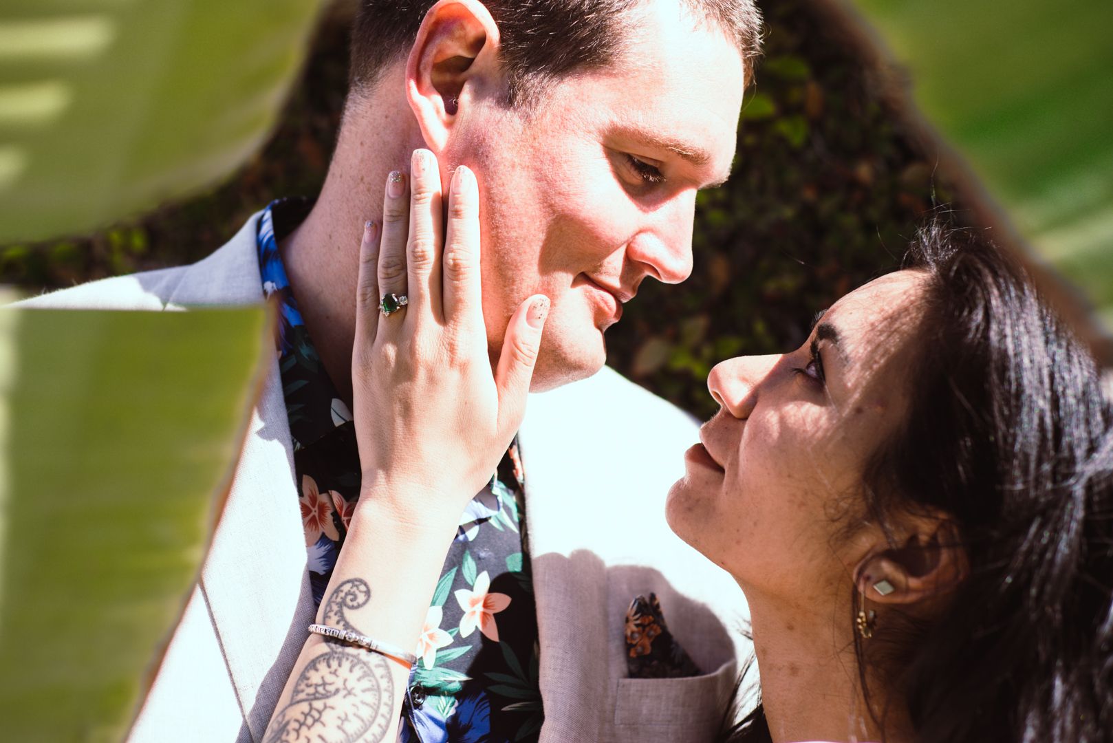 A couple shares an intimate close-up moment outdoors in natural lighting.
