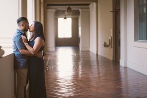 Intimate couple moment in sunlit hallway with terracotta floors.