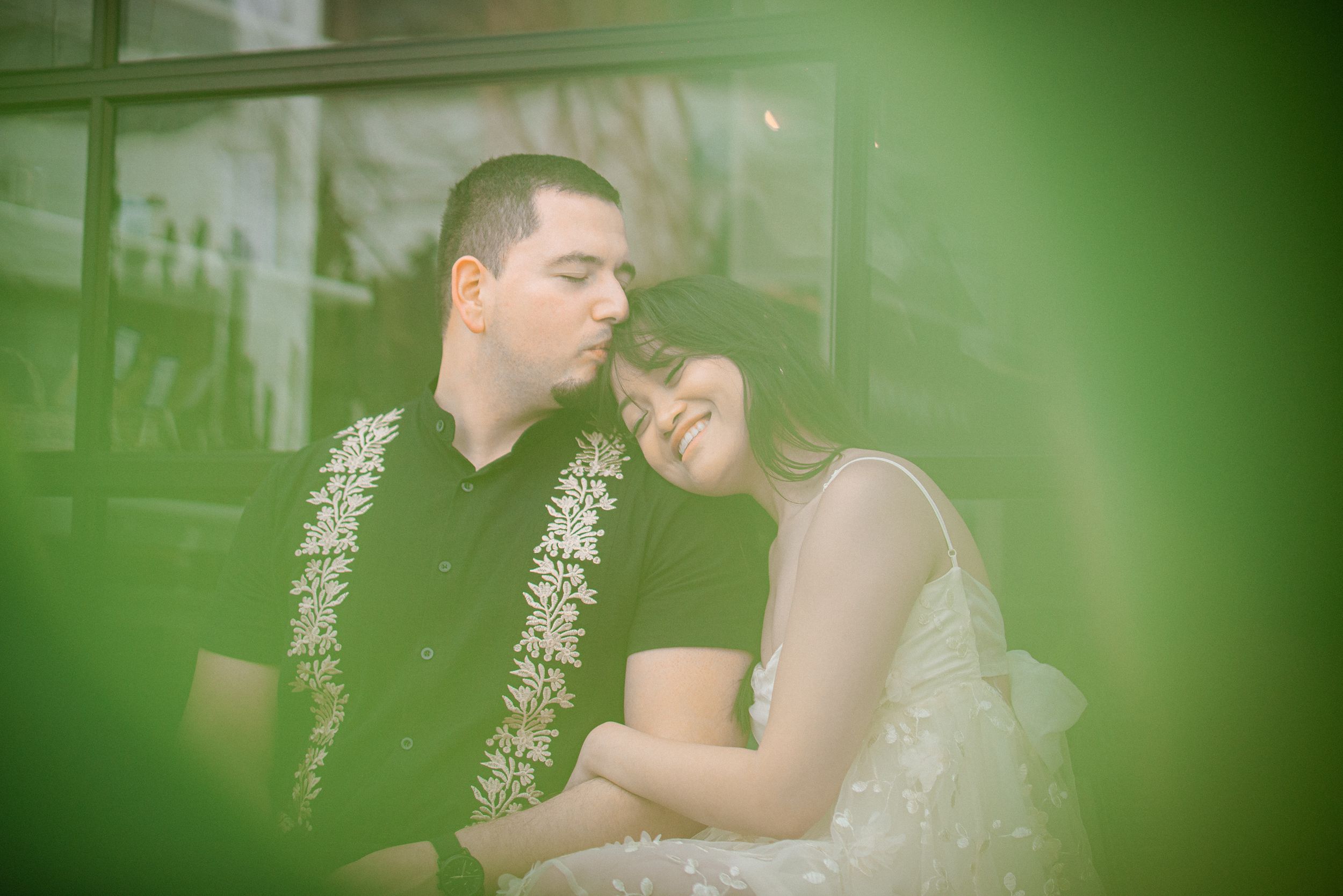 A romantic couple moment captured through green-tinted glass.