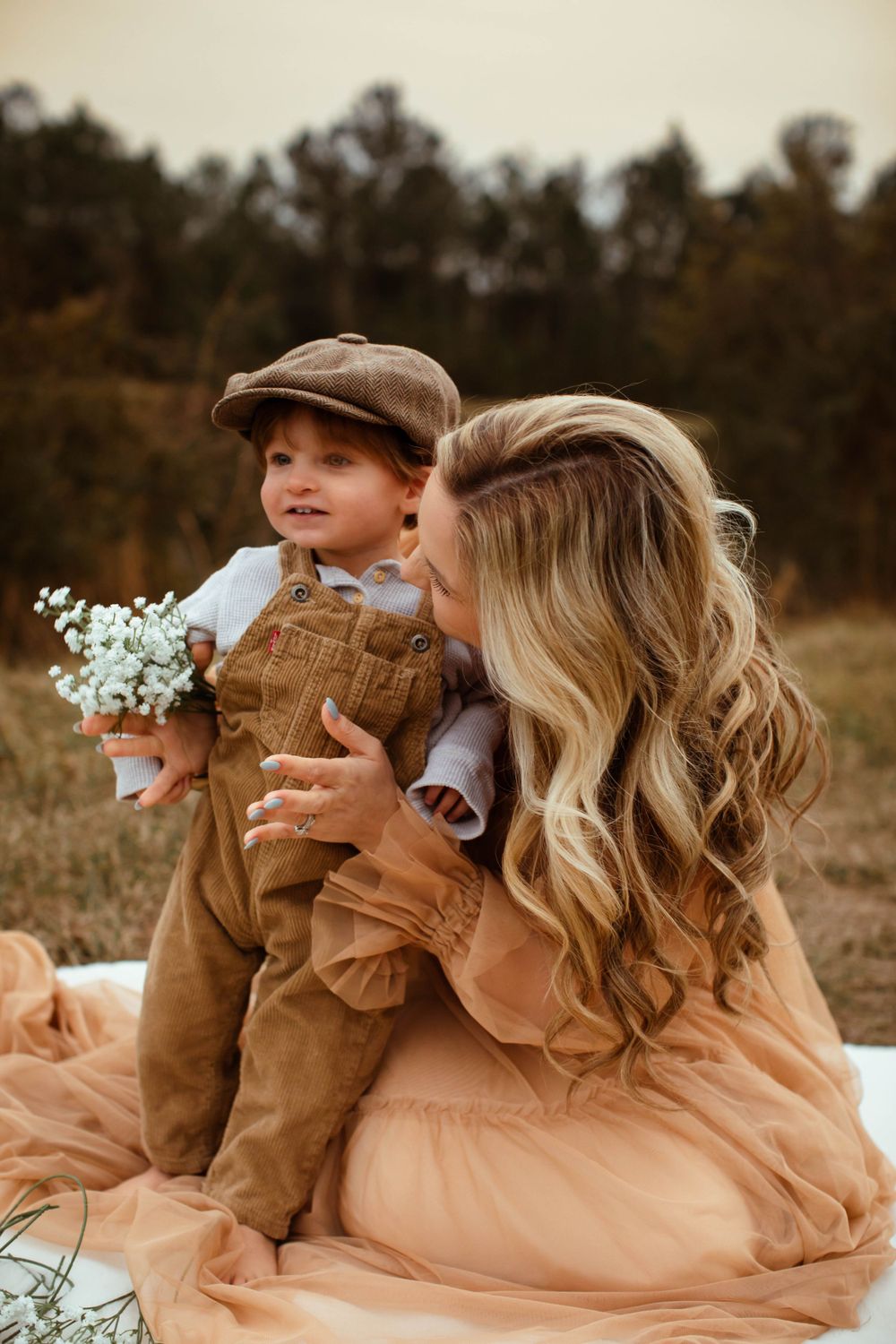 A sweet autumn portrait featuring corduroy overalls, a peach dress and delicate baby's breath flowers in a rustic outdoor setting.