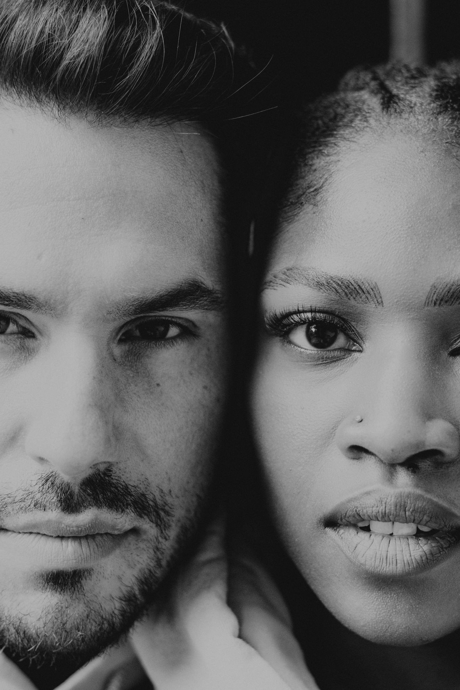 Intimate black and white close-up portrait of couple's faces side by side.