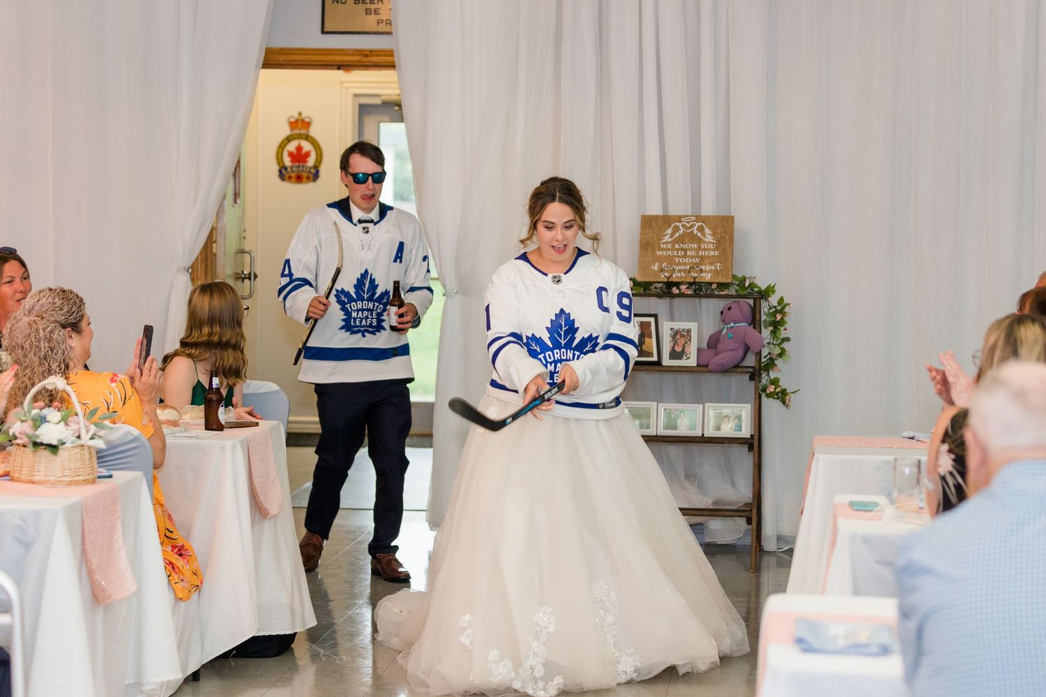 Couple wearing Toronto Maple Leafs jerseys during their wedding reception entrance.