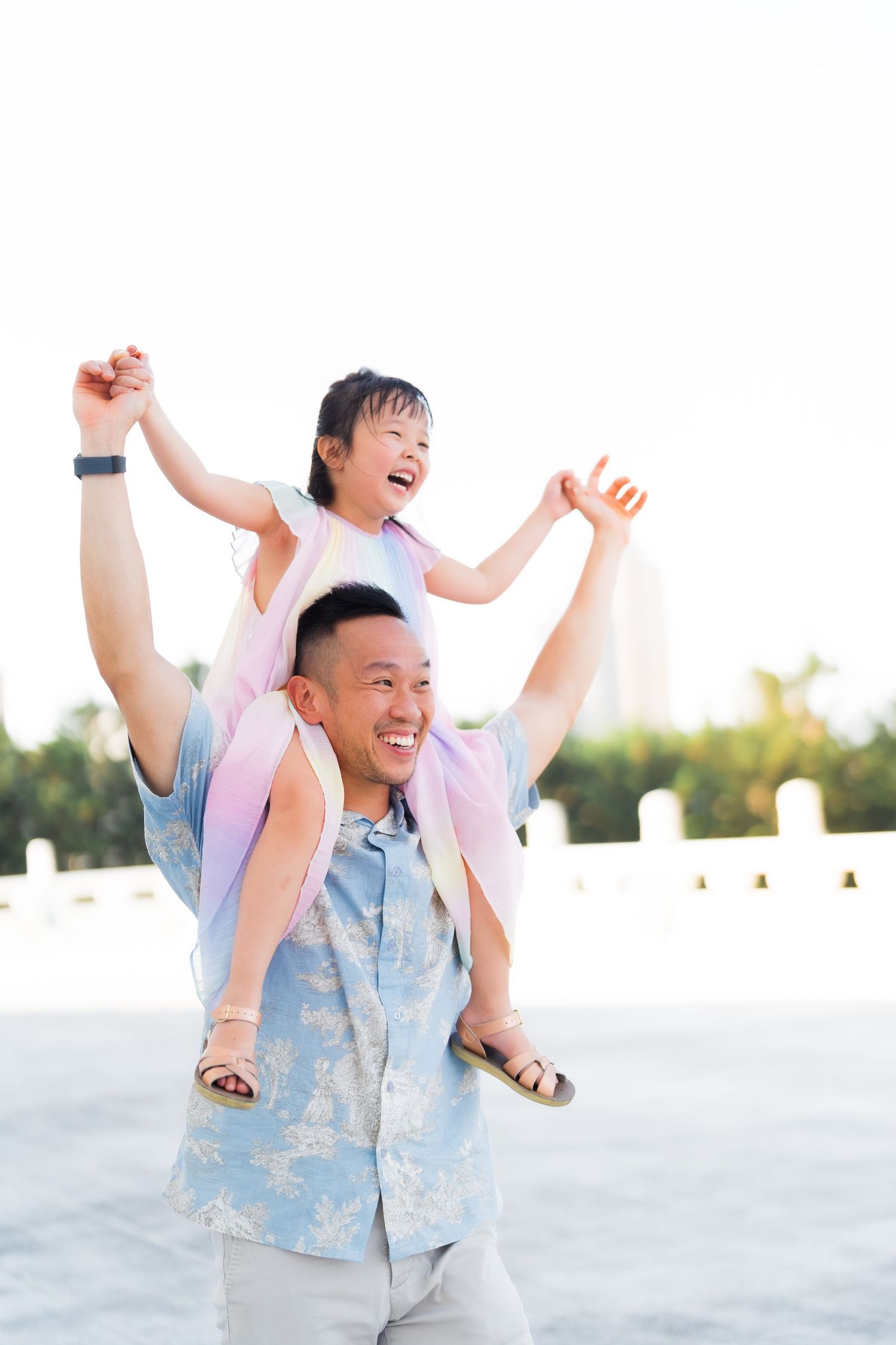 A joyful moment captured outdoors with playful expressions and raised arms.
