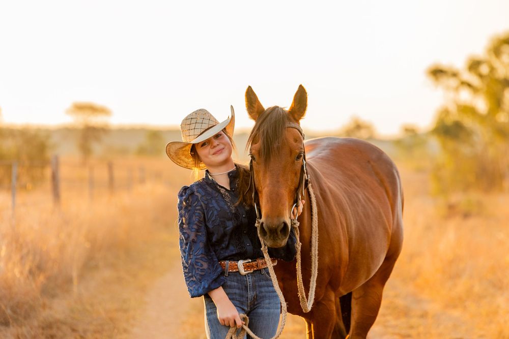 Horse and companion share tender moment in golden outback sunset.