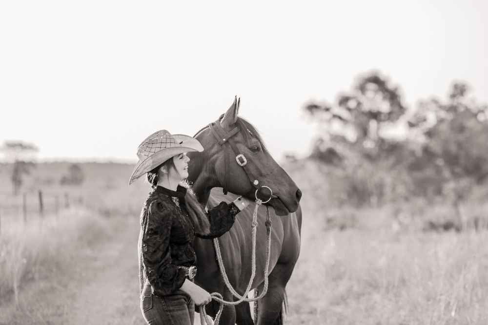 Black and white portrait of horse and companion bonding in rural setting.