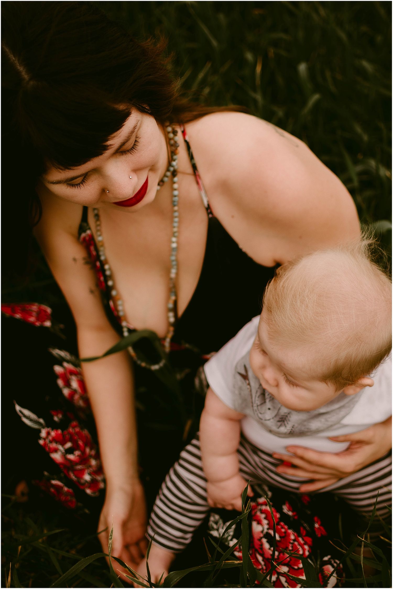 Close-up shot showing tender interaction between parent and baby outdoors in summer attire.