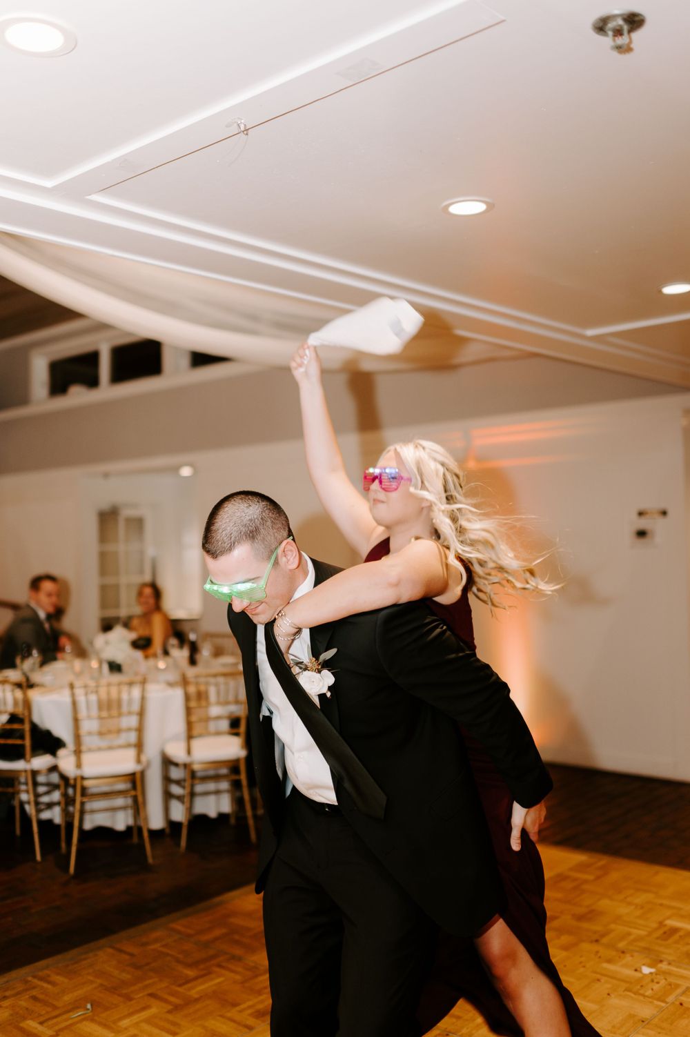 Guests show off dynamic dance moves during wedding reception in elegant ballroom.