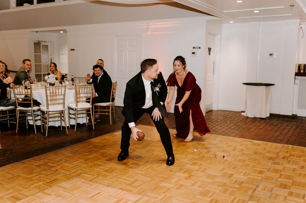 Wedding celebration features lively dancing on parquet floor with elegant white decor.