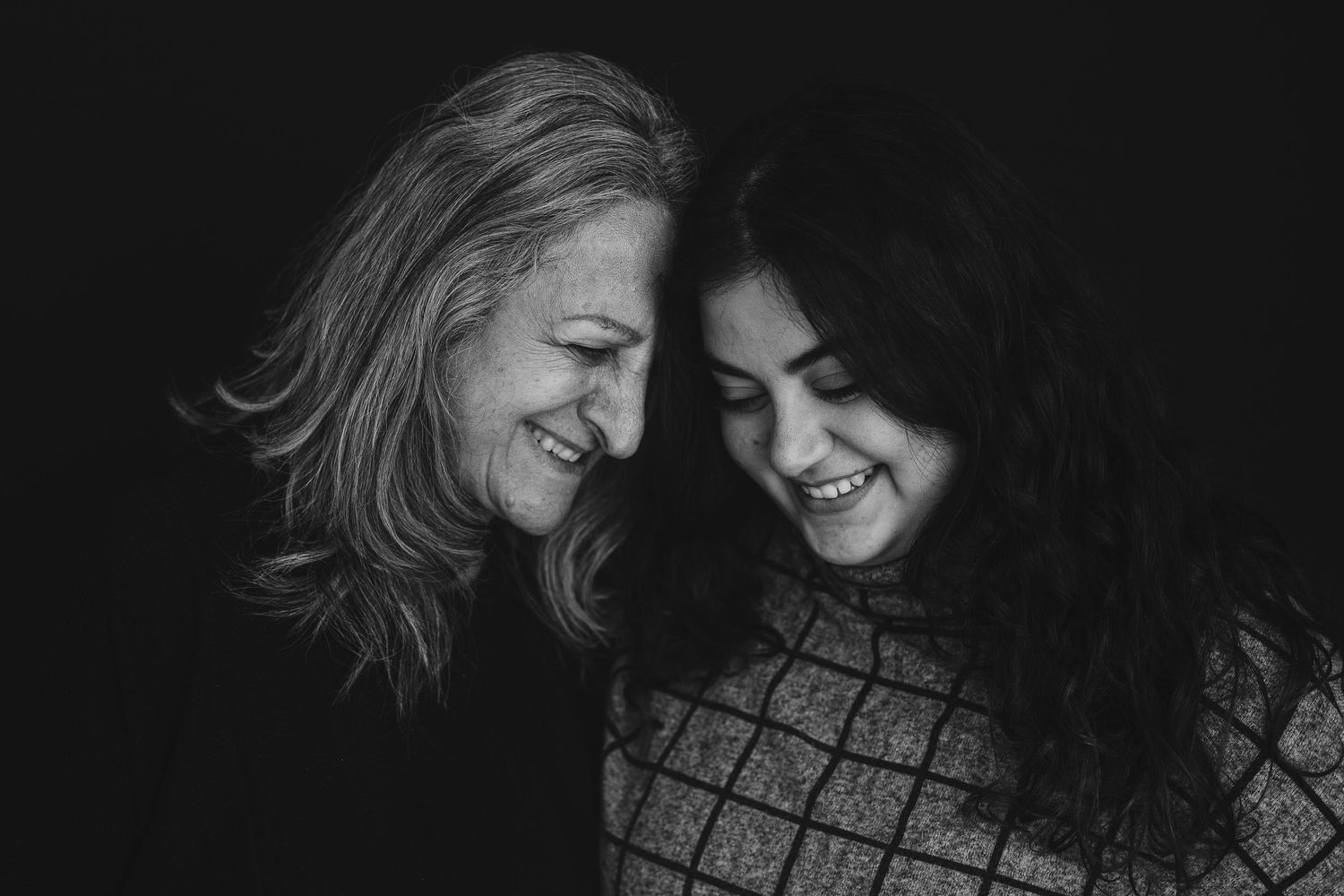 Black and white portrait capturing authentic laughter between two people in intimate moment.