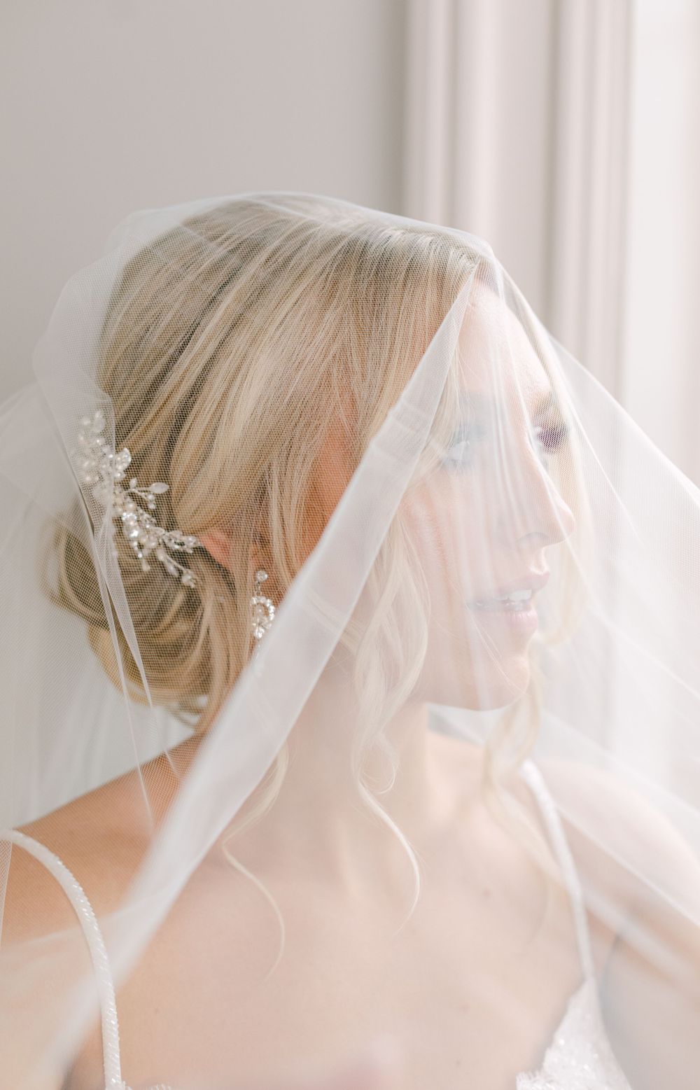 Close-up bridal portrait through delicate veil showing detailed hair accessory and soft makeup.