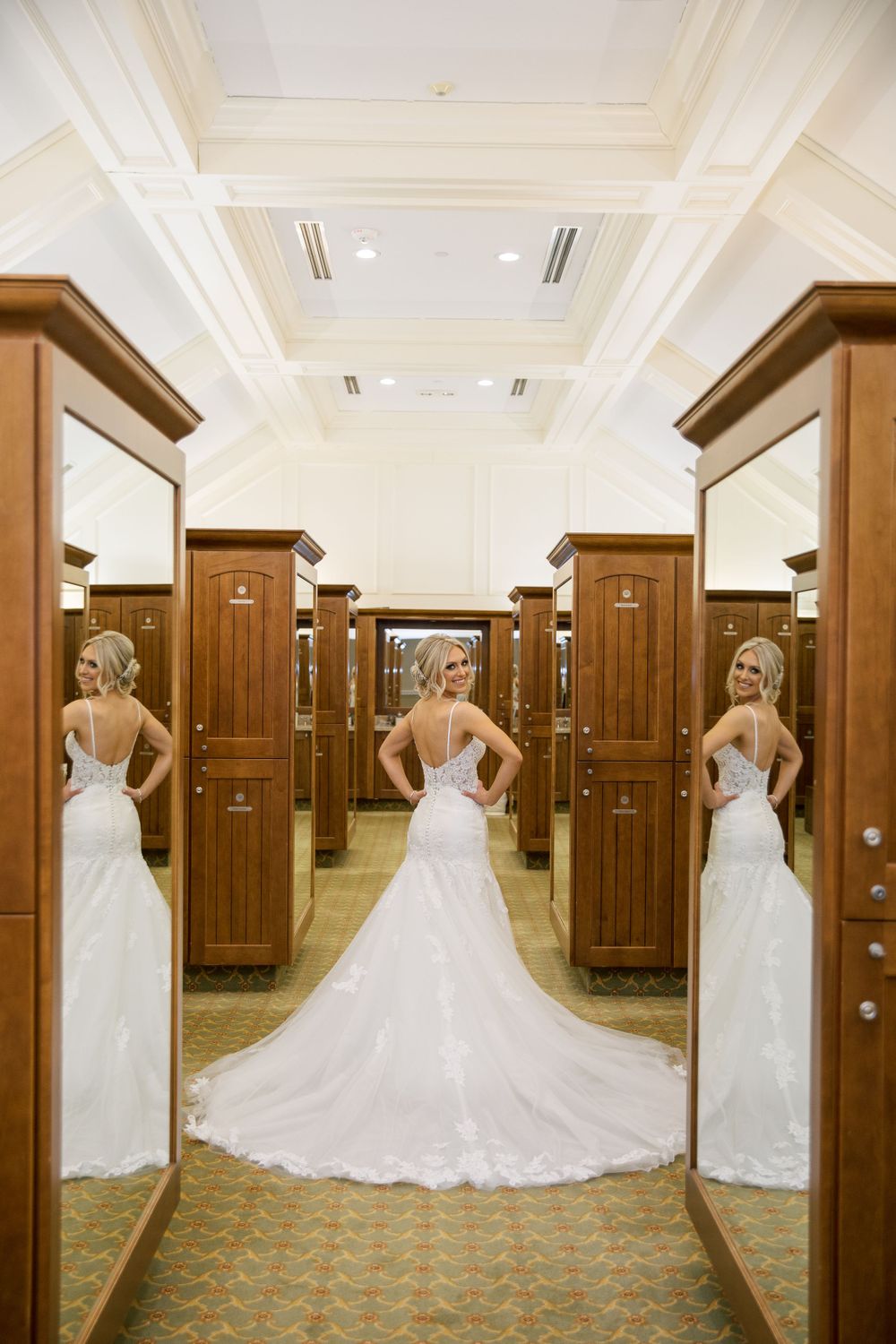 Wedding dress reflection in triple mirror showing elegant train and backless design.
