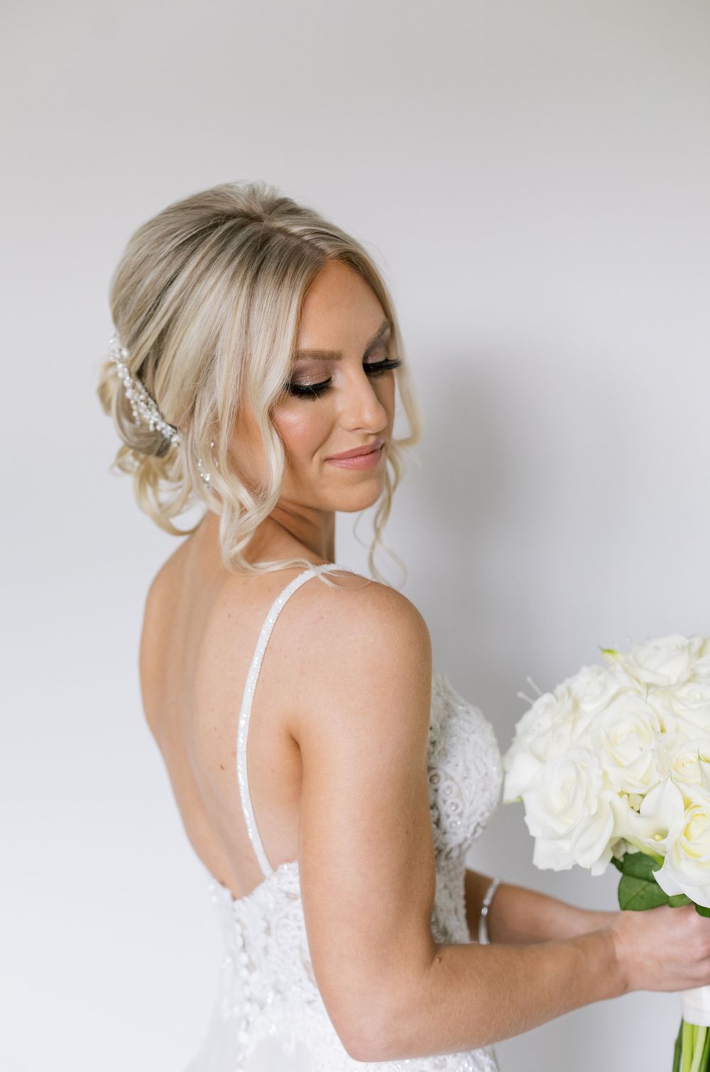 Side profile of bride with elegant updo hairstyle holding white bouquet.
