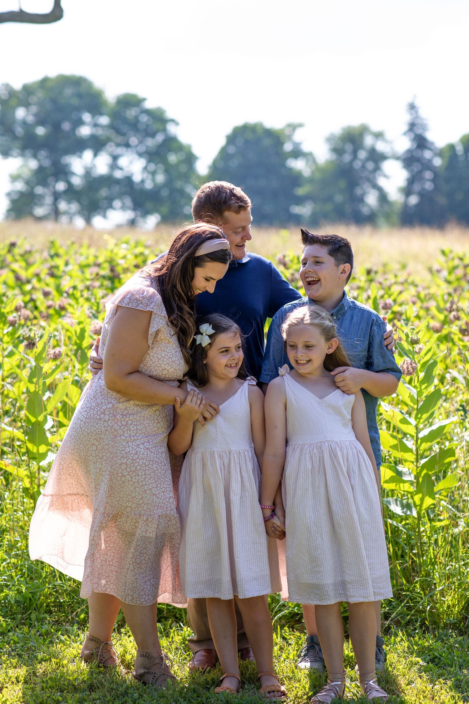 A happy family shares laughter together in a sunny sunflower field.