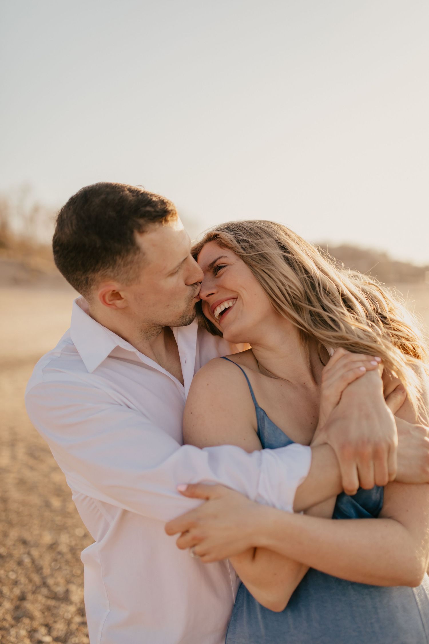 Playful couple embraces and laughs during golden hour photoshoot.