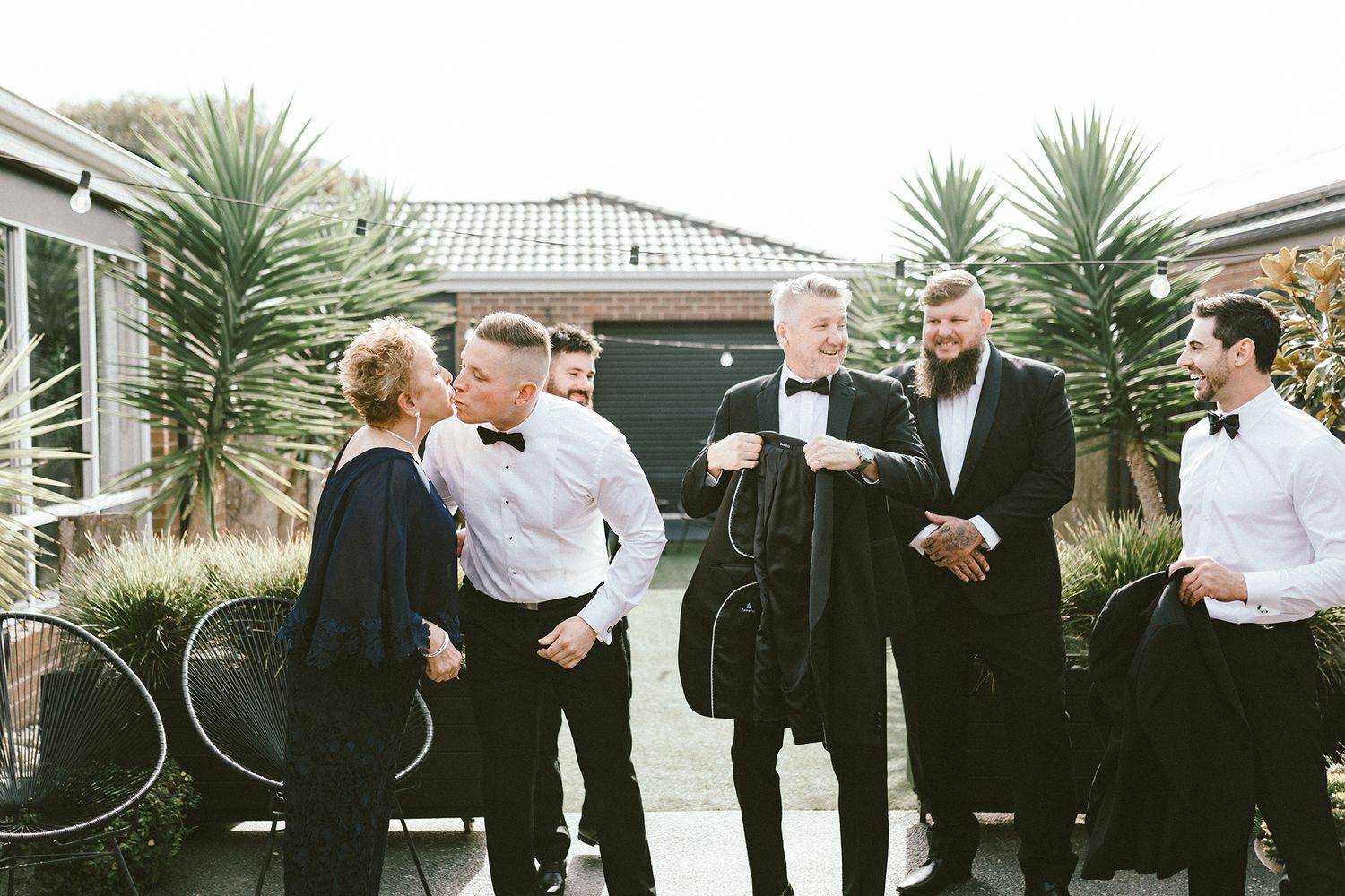 A formal gathering outside a modern building with palm trees in the background.