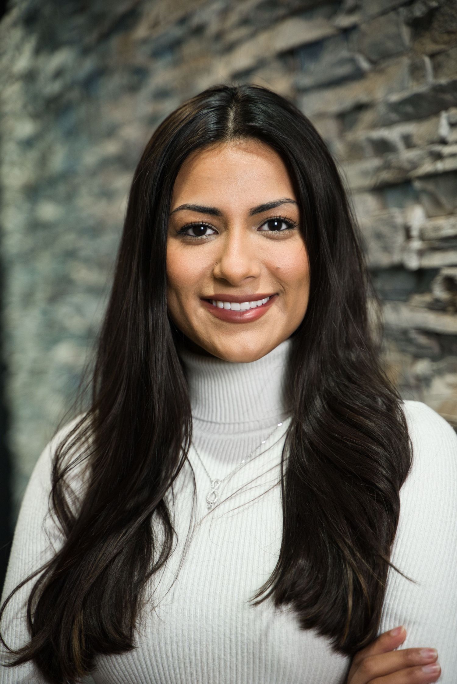 Professional studio portrait against a textured stone wall background.