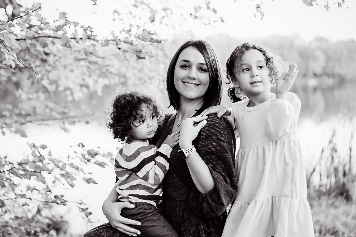A family portrait by a lake with spring blossoms in black and white.