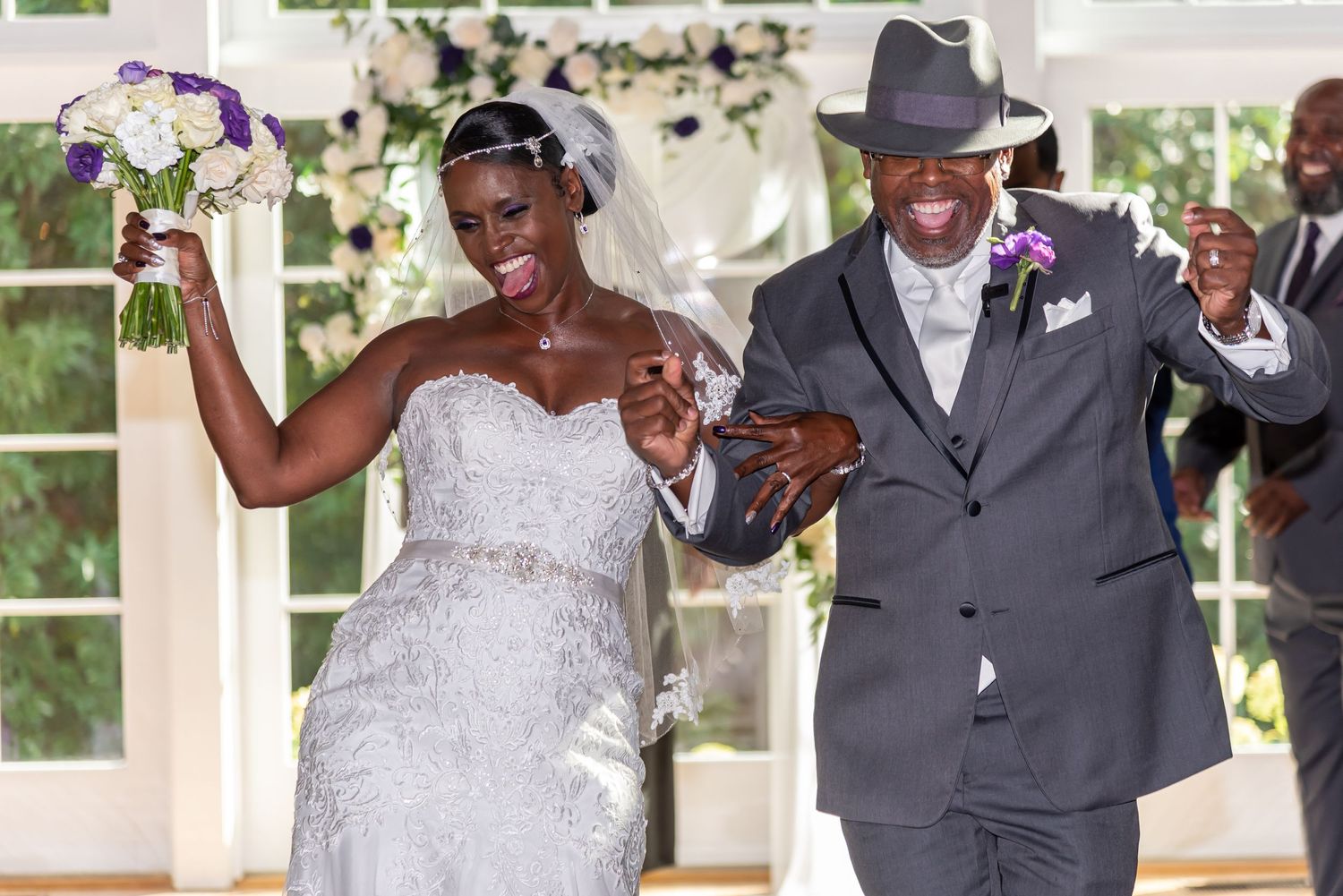 Jubilant newlyweds celebrating during wedding ceremony under white gazebo.