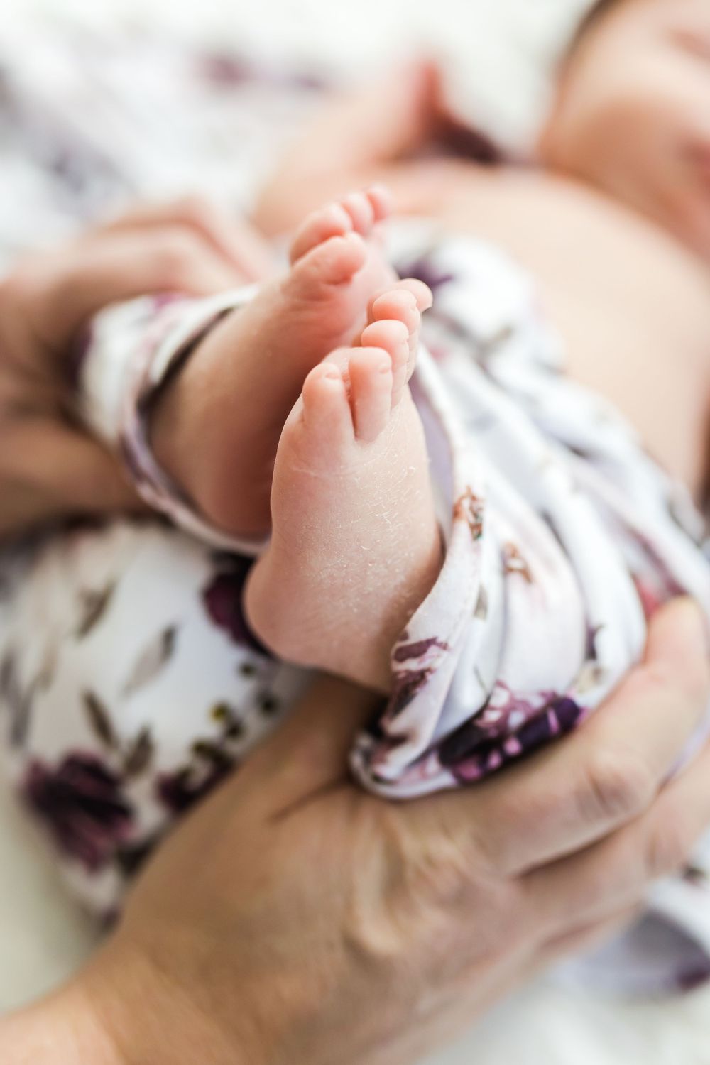 Close-up of tiny baby feet in delicate floral clothing.