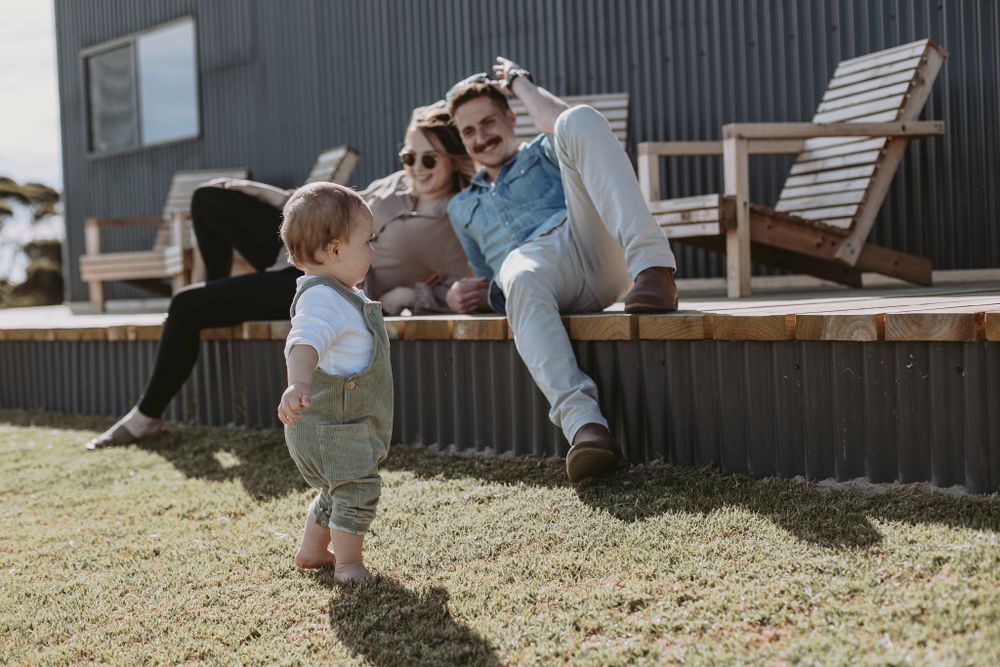 Family sitting together outdoors on wooden deck chairs enjoying a sunny day.