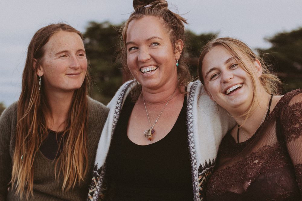 A group of friends laughing and embracing outdoors during a casual gathering.