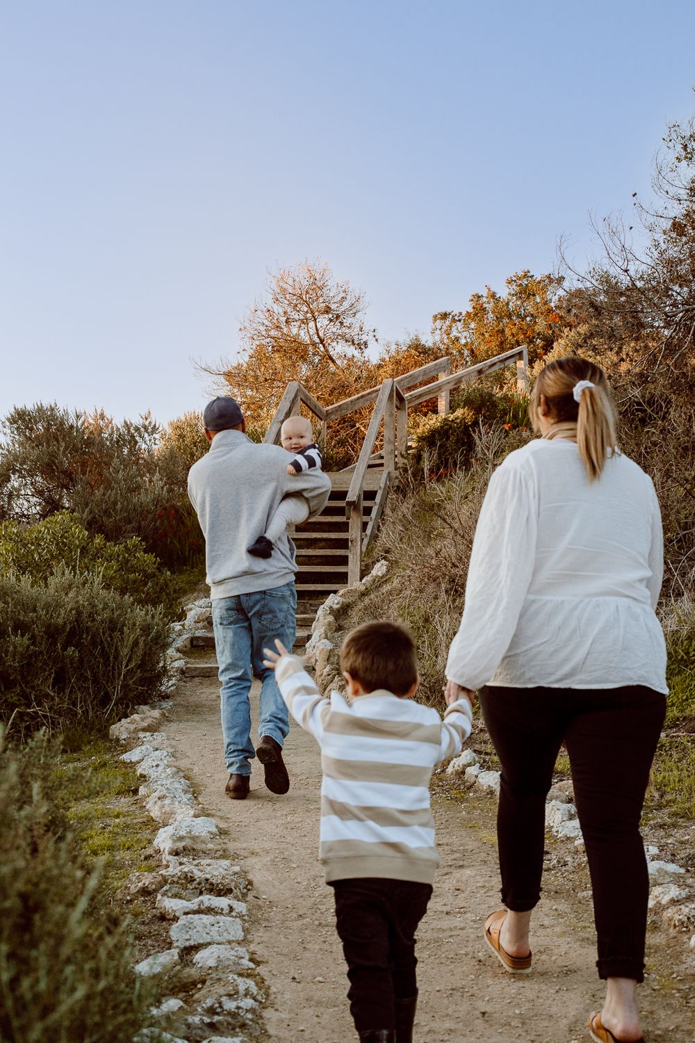 Family walking together on a nature trail during sunset.
