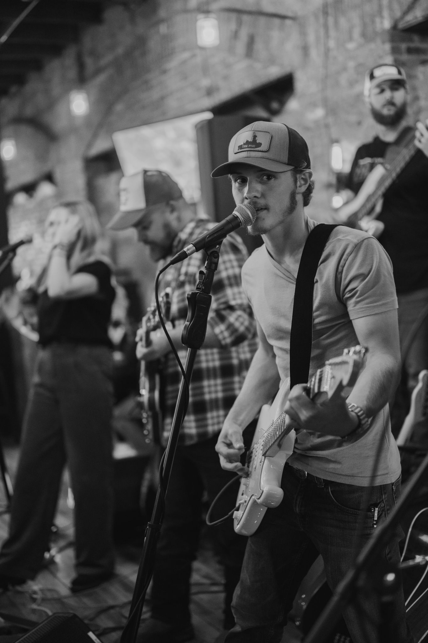 Musicians playing instruments on stage at a rustic indoor venue.