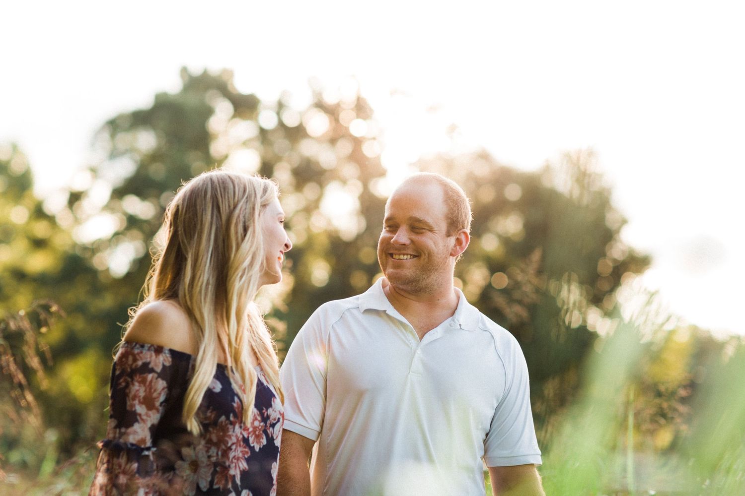 Couple embraces outdoors during a sunset photoshoot with natural backlit glow.