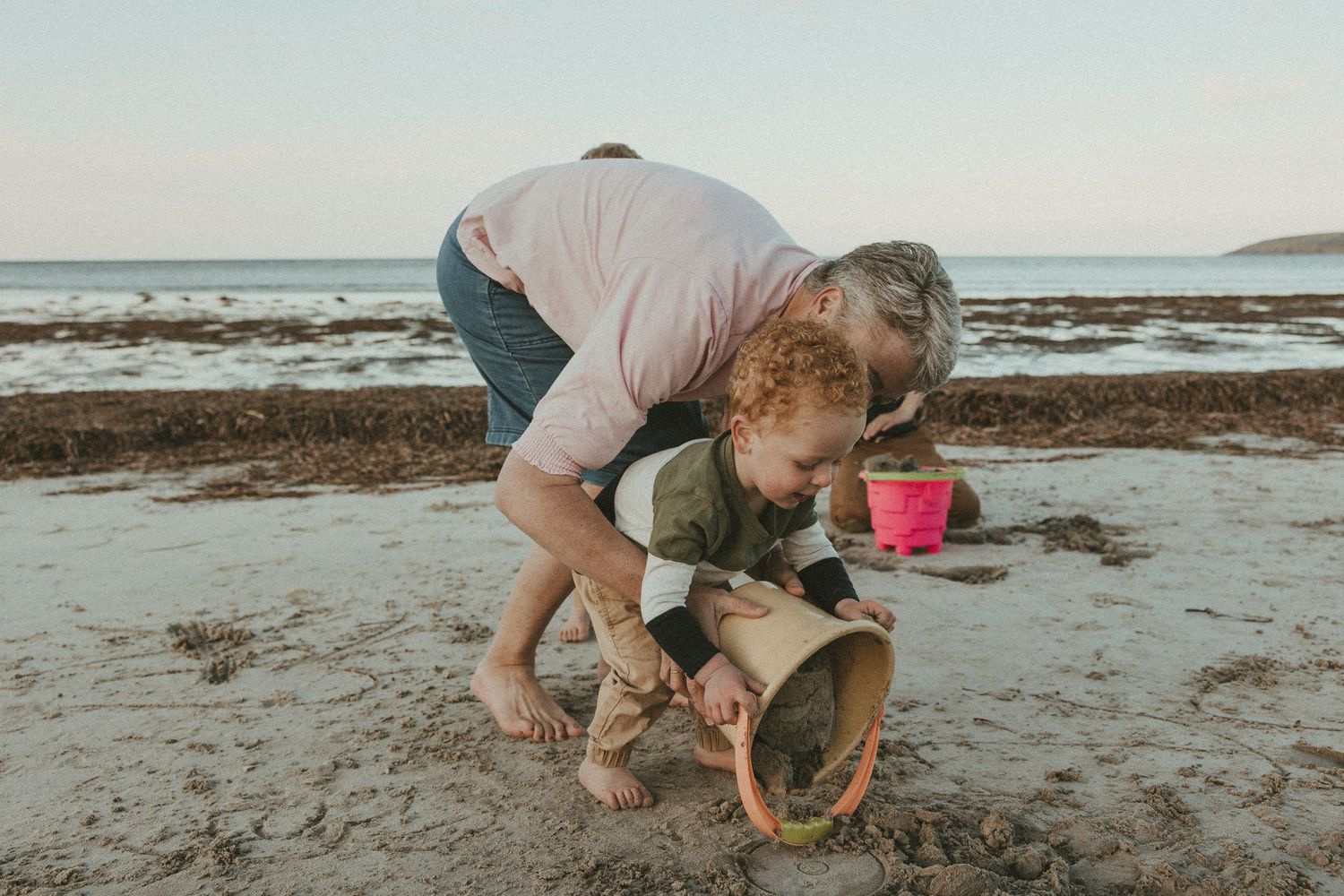 People exploring and playing on a sandy beach during low tide.