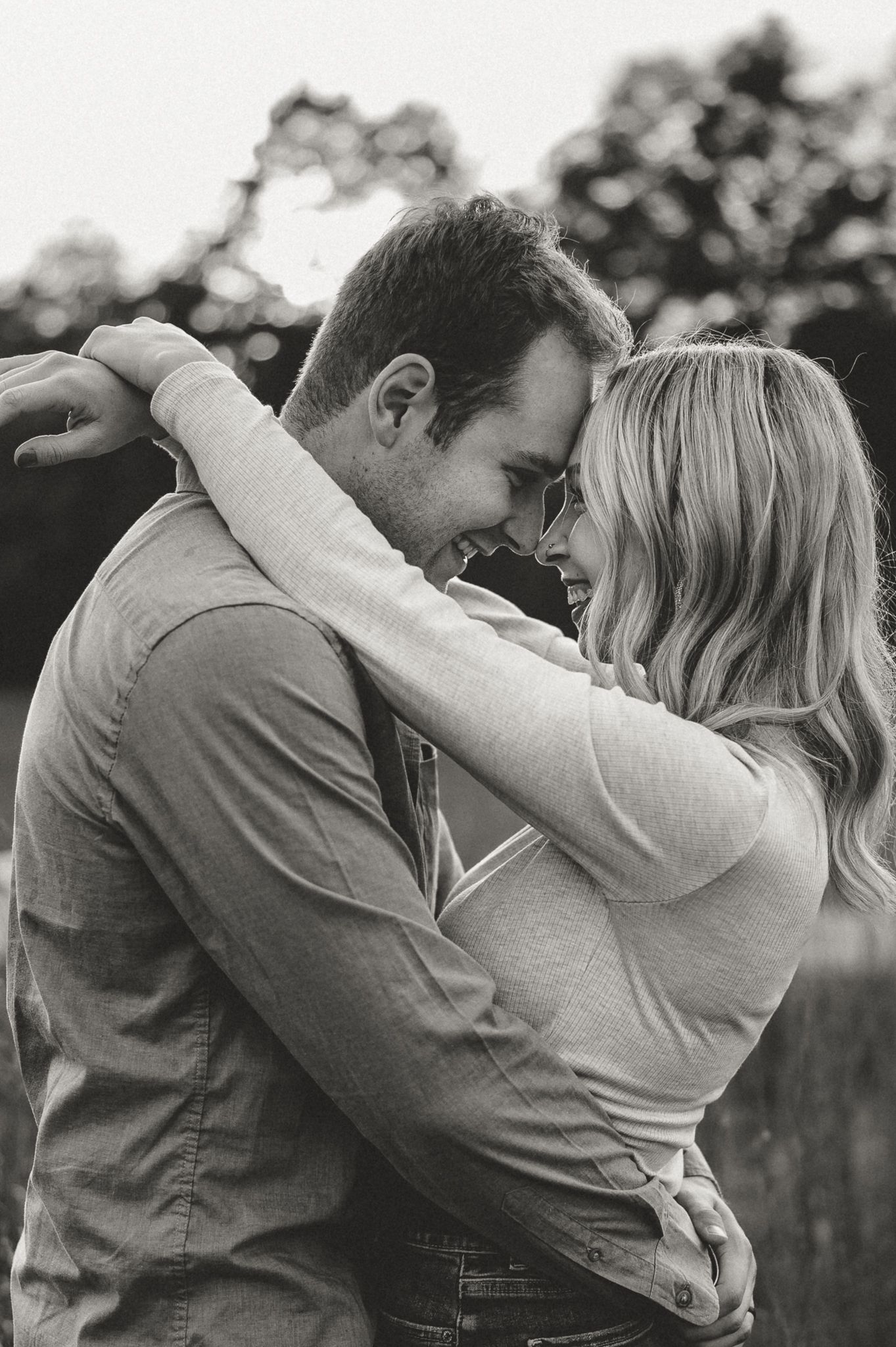 An intimate black and white portrait of a couple embracing outdoors.
