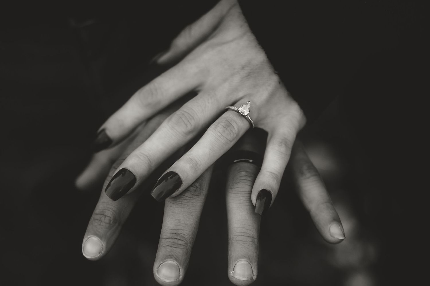 Black and white close-up of a diamond engagement ring on a manicured hand. rockford il
