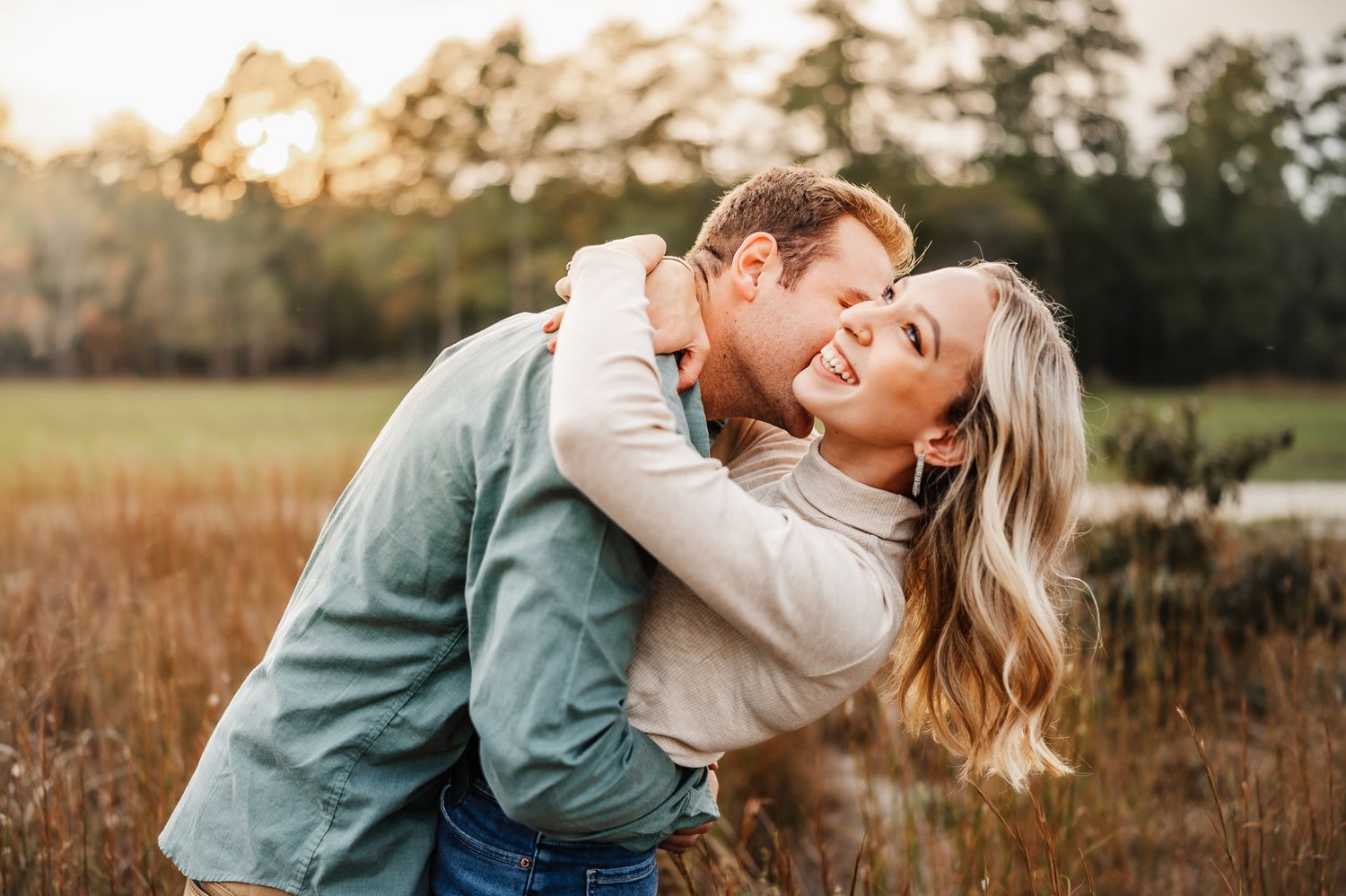A tender moment between a couple during golden hour in a rustic field setting.