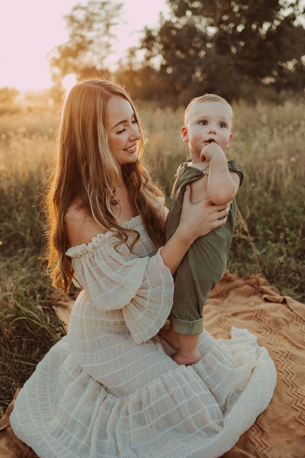 golden hour snuggles with mom during family photography session in a field