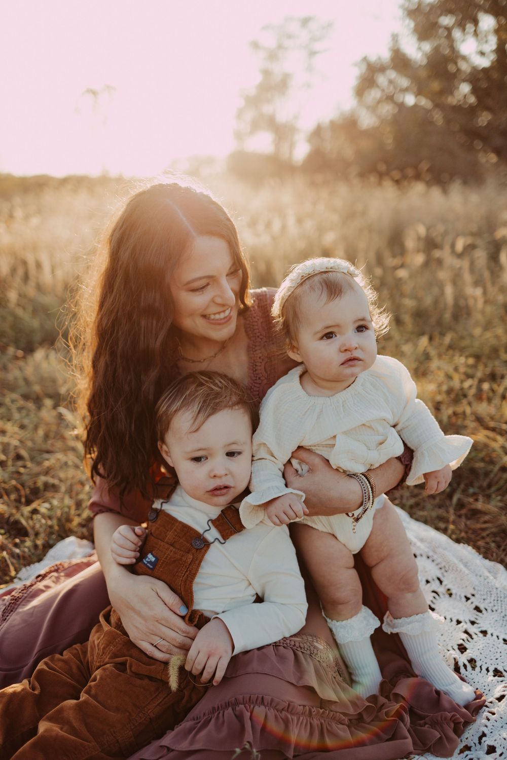 sitting on a blanket in the field with mom during family photography session