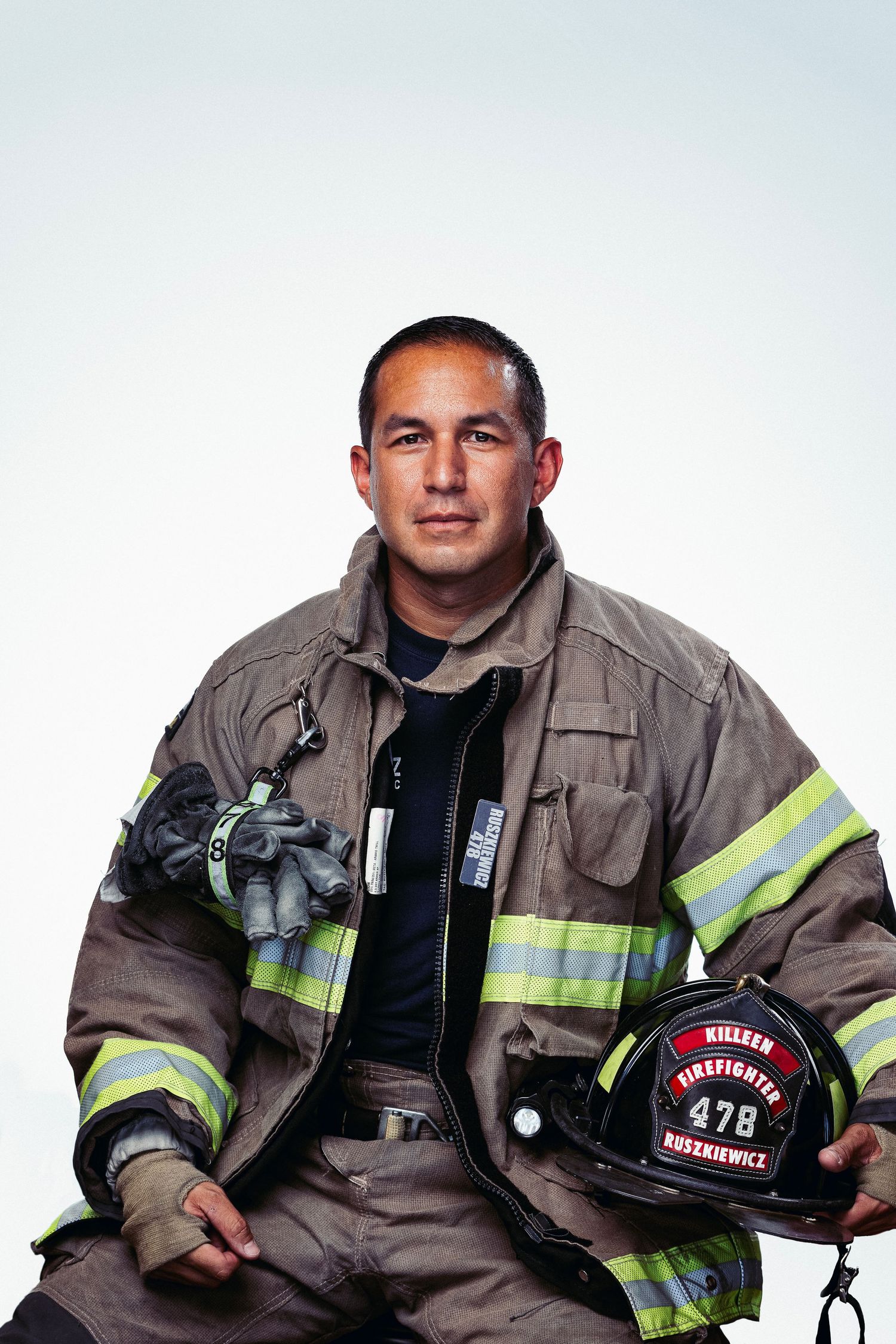 Firefighter in protective uniform posing with helmet and equipment.