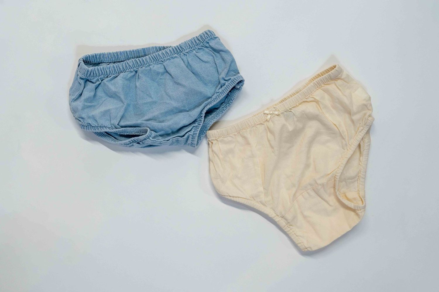 Two baby diaper covers in light blue and cream colors on white background.