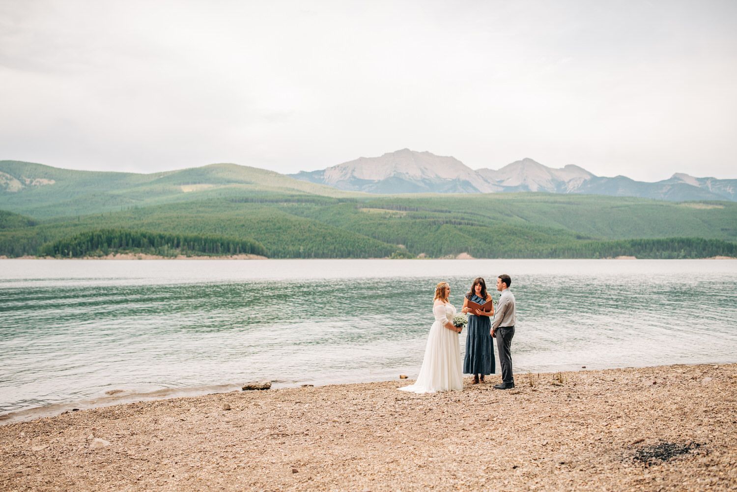 Couple standing alone on shore of lake, eloping with an officiant in Montana