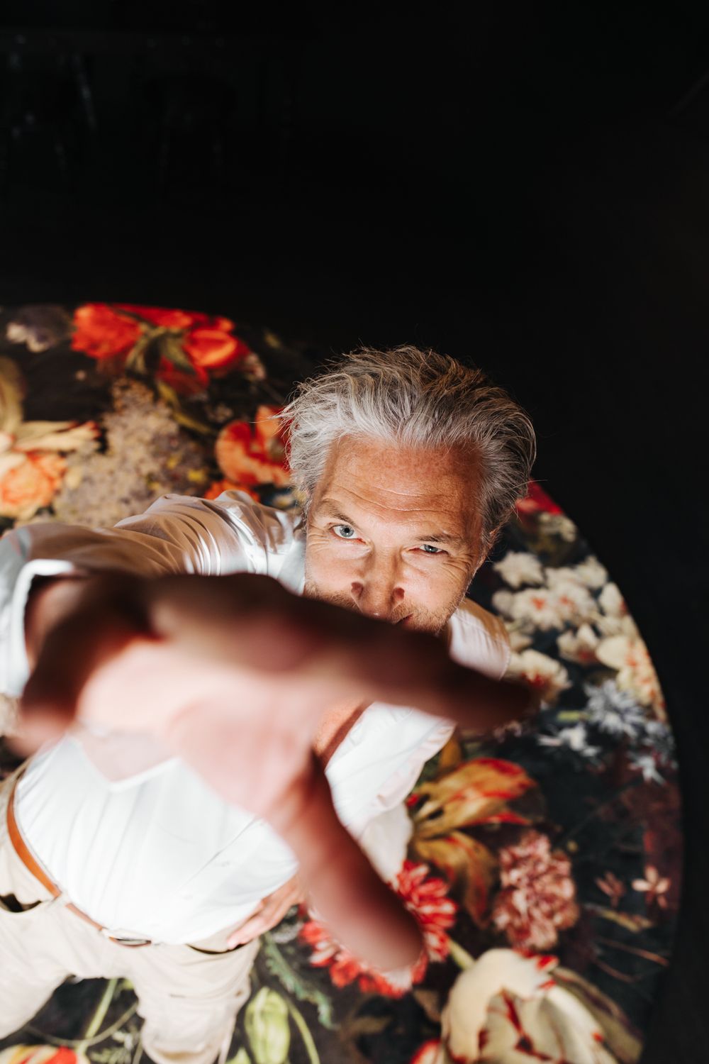A creative overhead shot of someone reaching toward the camera while lying on floral pattern.