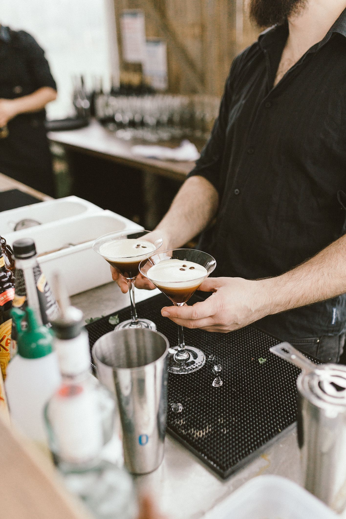 Bartender preparing an espresso martini with various cocktail ingredients on the bar.