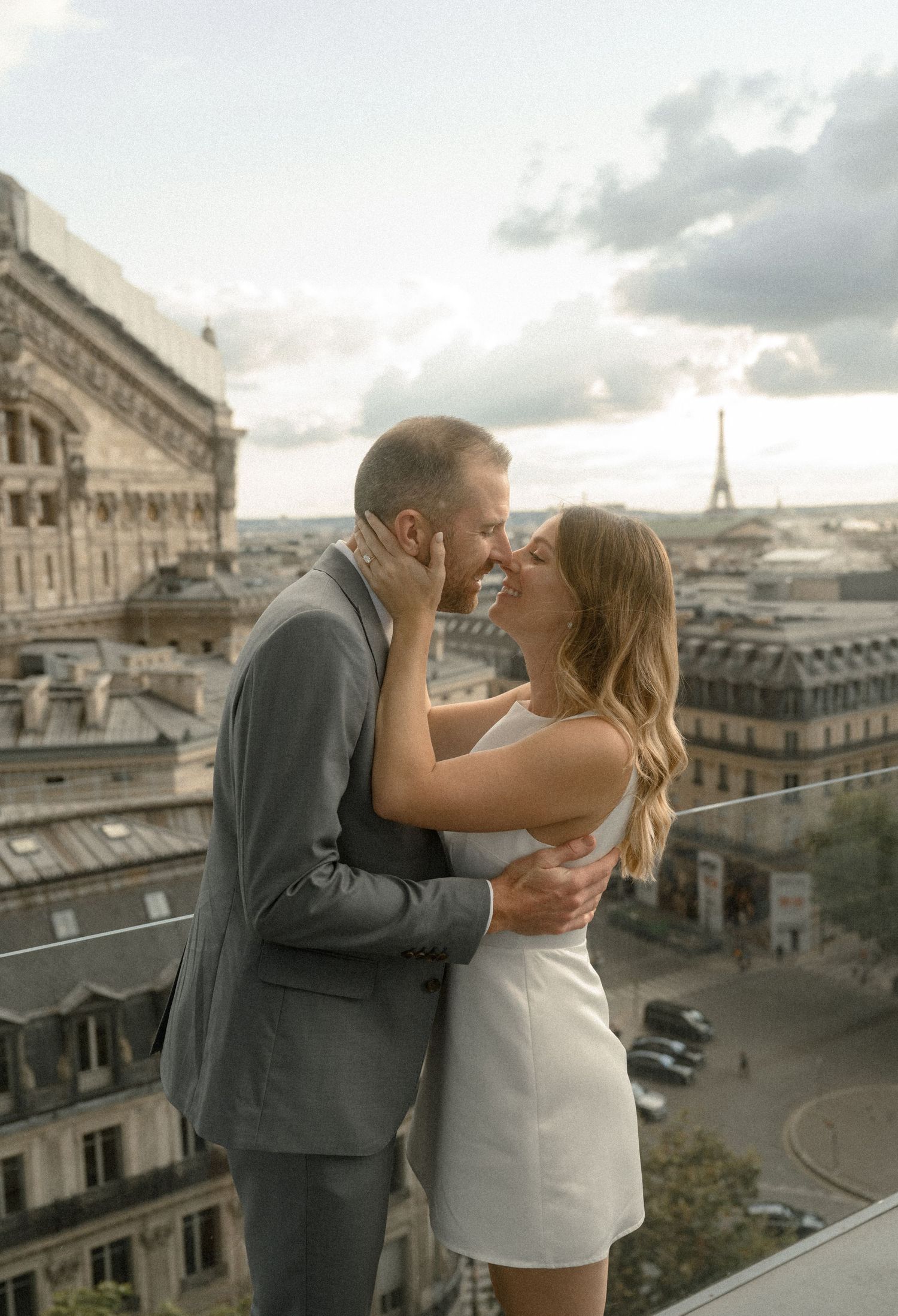Romantic moment shared between couple on Parisian rooftop with Eiffel Tower in background.