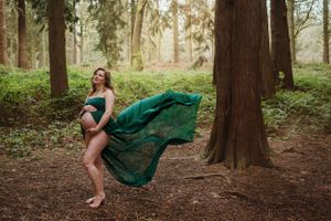 A flowing emerald green dress twirls through a misty forest landscape.