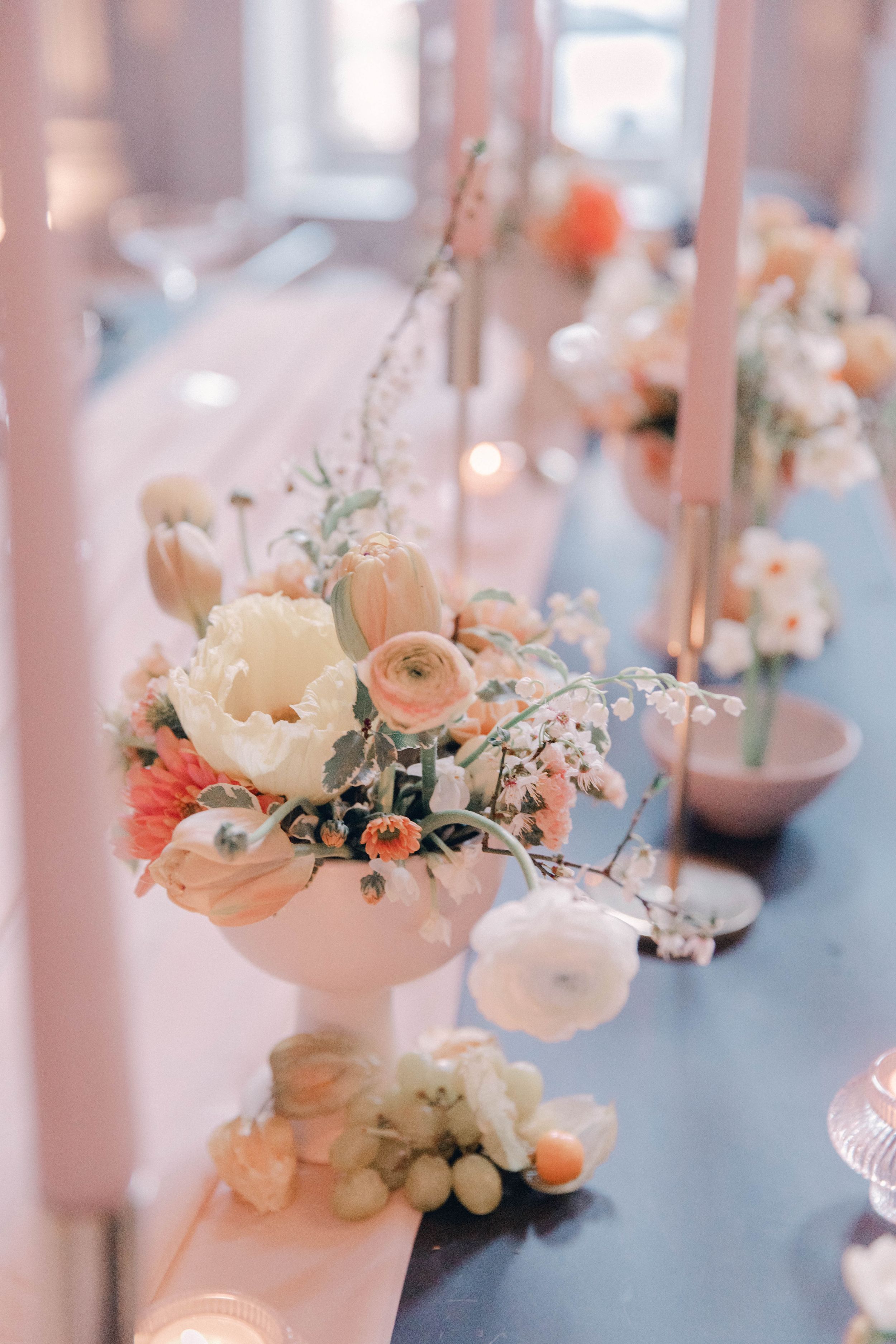 Delicate floral arrangements with white and peach blooms adorning wedding reception tables.