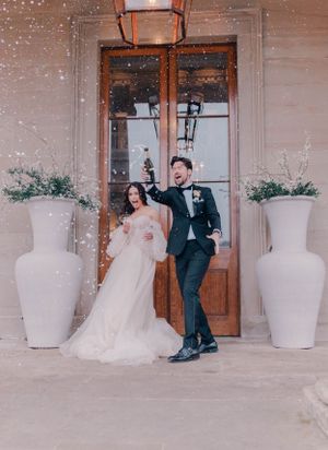 Wedding couple sitting on steps outside venue with white decorative planters.