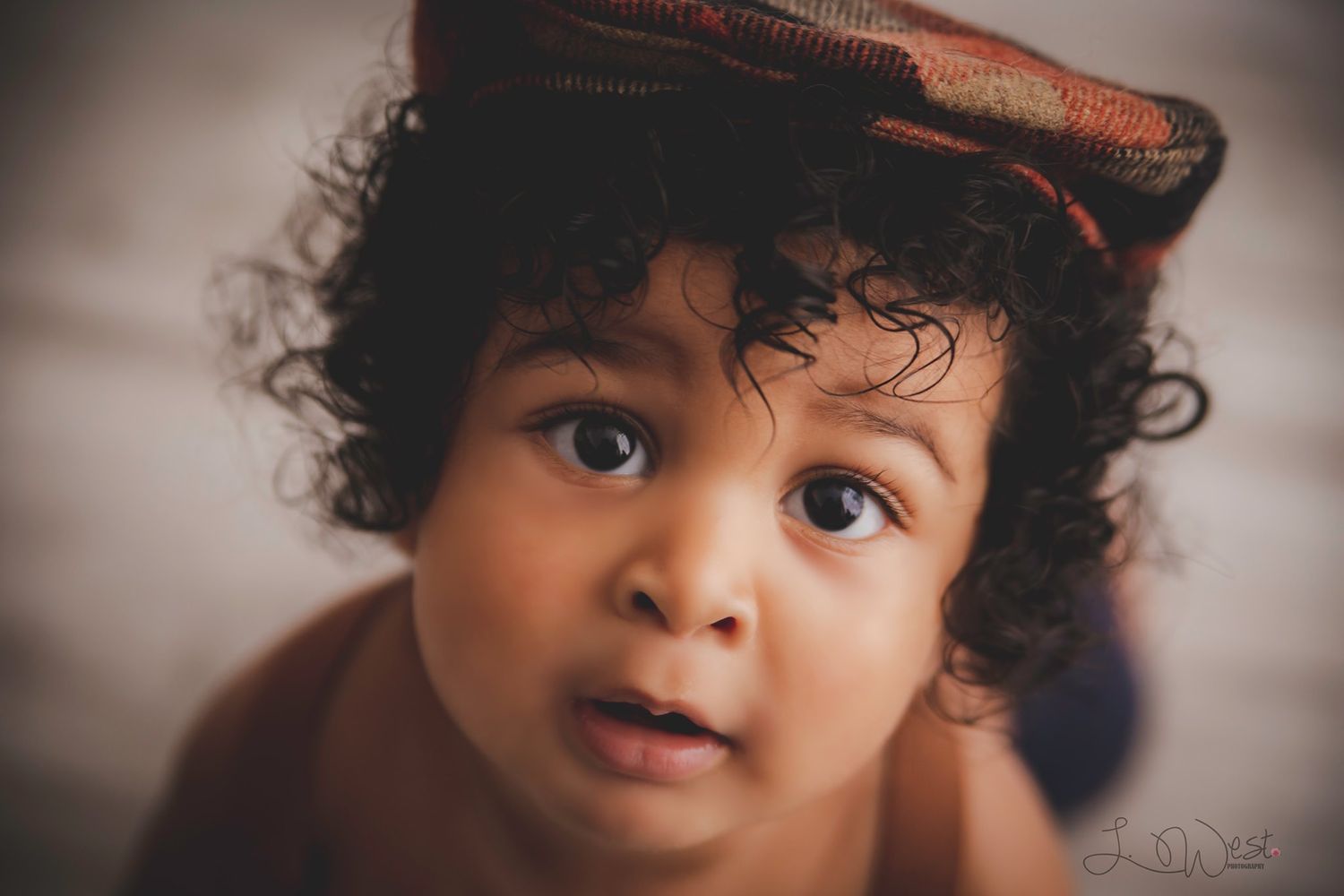 Artistic close-up portrait with brown cap and neutral background.