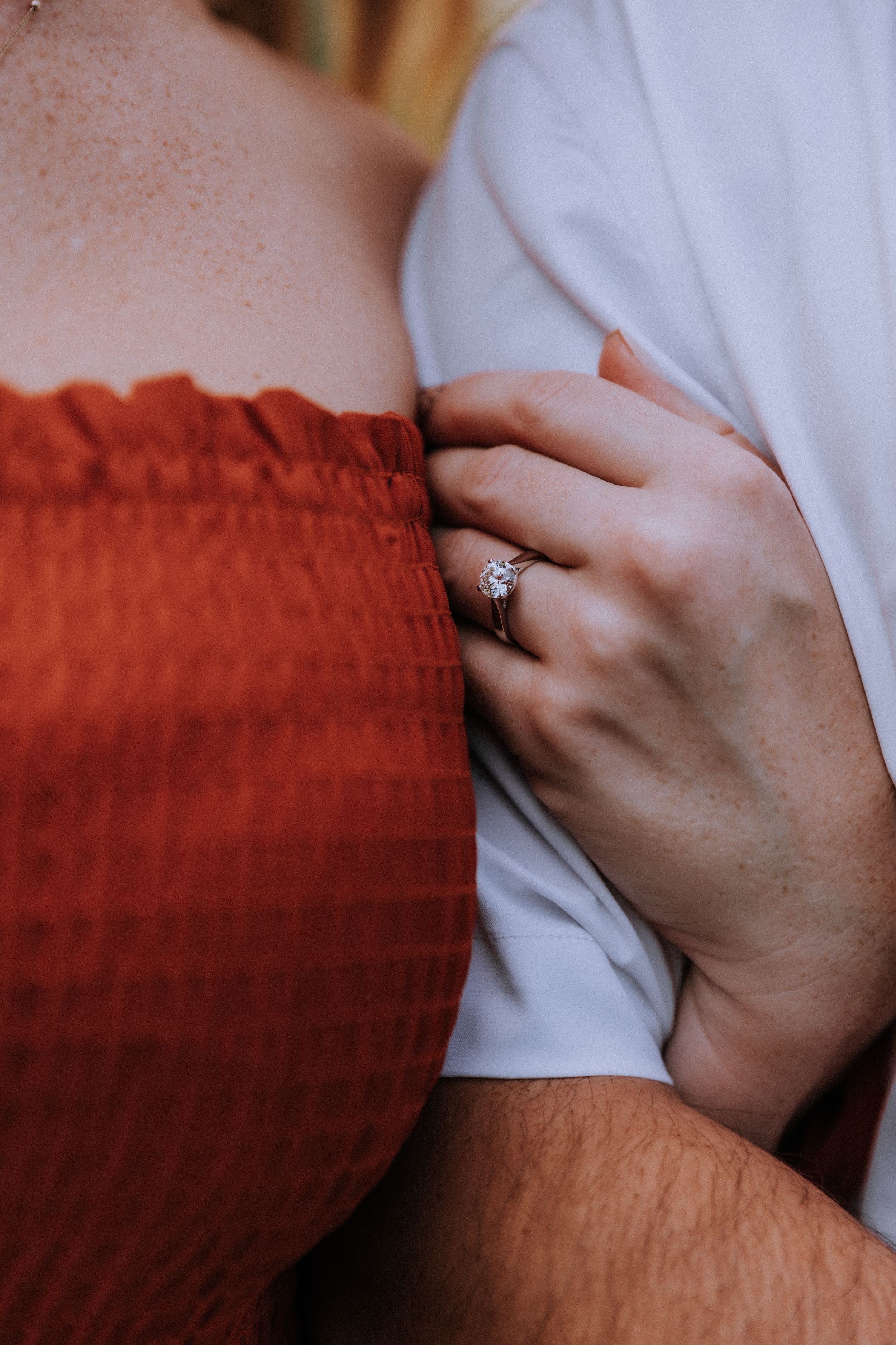 Close-up detail of hands against white shirt and red fabric.