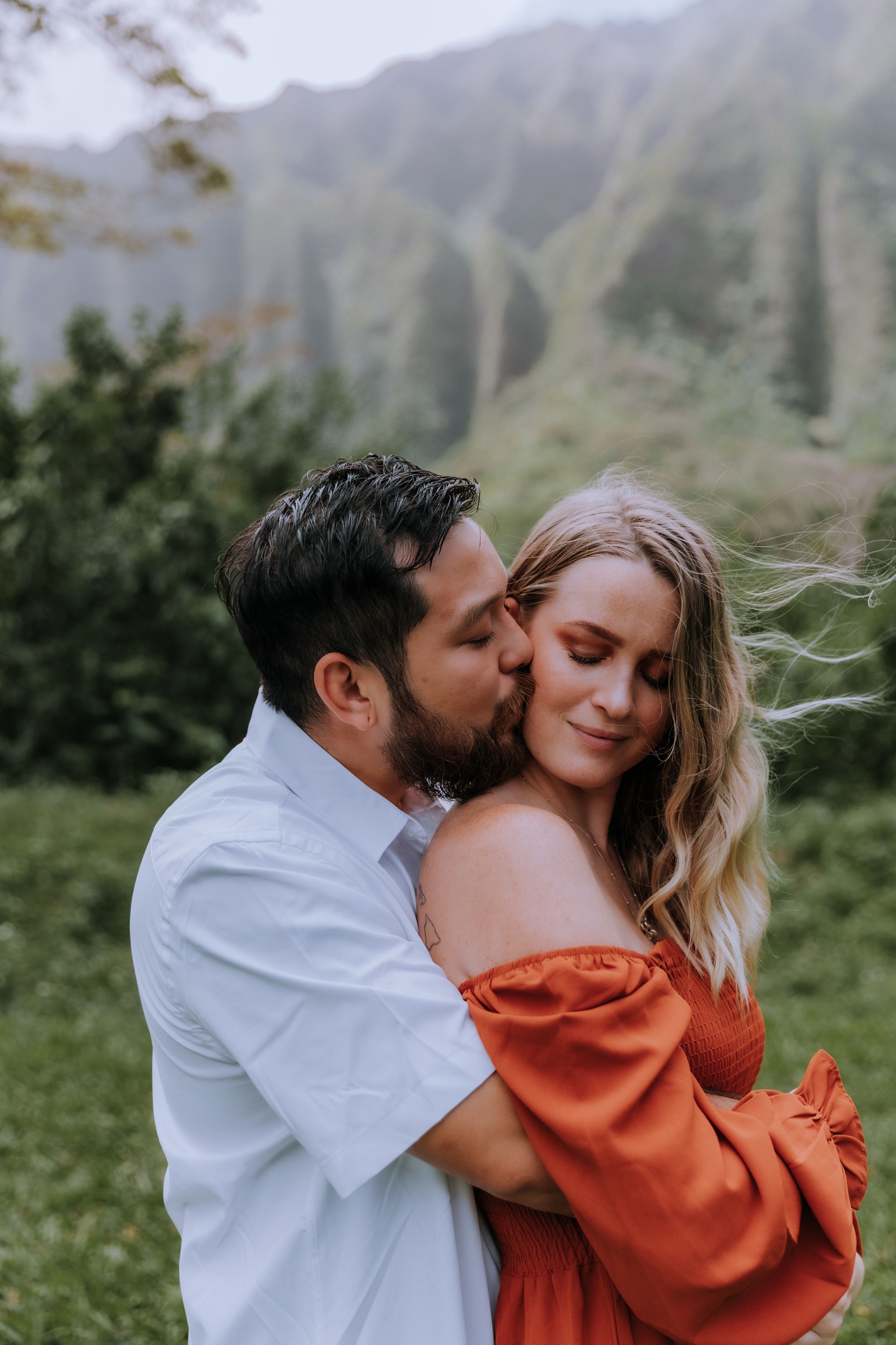 Romantic couple embracing in front of misty mountain landscape.