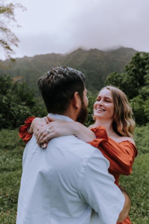 Joyful embrace captured in front of foggy mountain scenery with lush greenery.