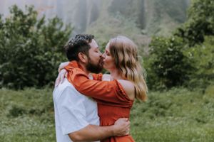 A happy couple celebrates their engagement in a scenic mountain location.