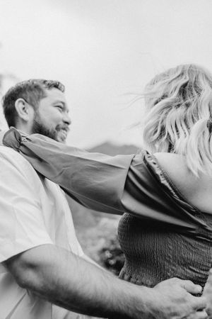 Black and white candid shot of couple in loving embrace outdoors.